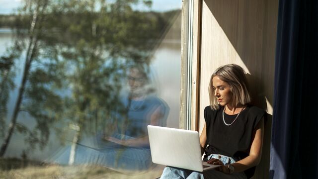 Woman working on laptop close to window